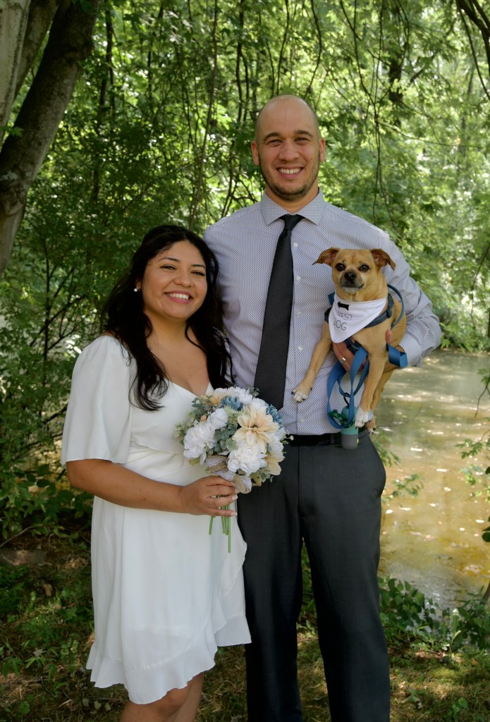 My wife, our dog, and I are standing in front of the creek on a sunny day. We got married that day, and in our backyard, with the tree above us giving enough shading, we stood there with the perfect picture.