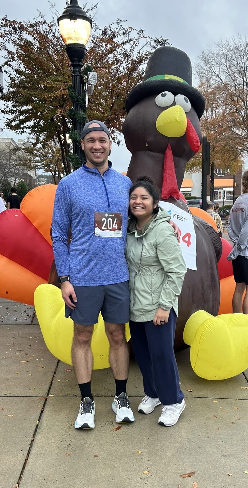 Me and my wife, standing in front of an inflatable turkey wearing a pilgrim hat.