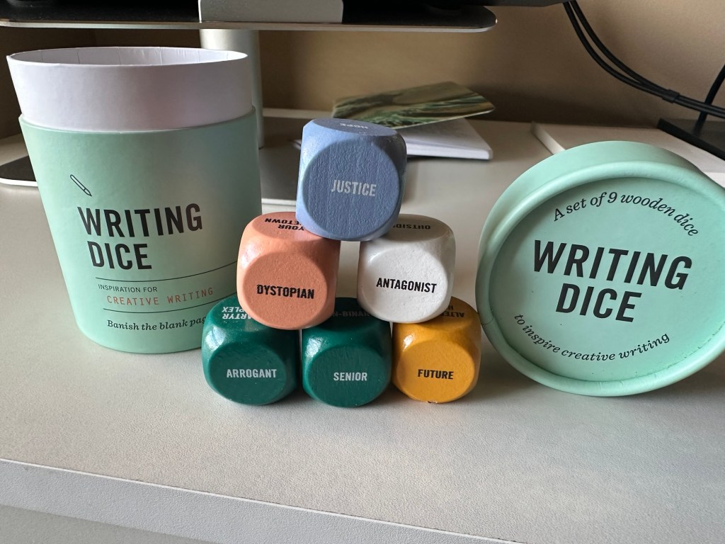 Five dice on top of each other. With the container and lid surrounding them. The dice read from top to bottom, left to right: Justice, Dystopian, Antagonist, Arrogant, Senior, Future.