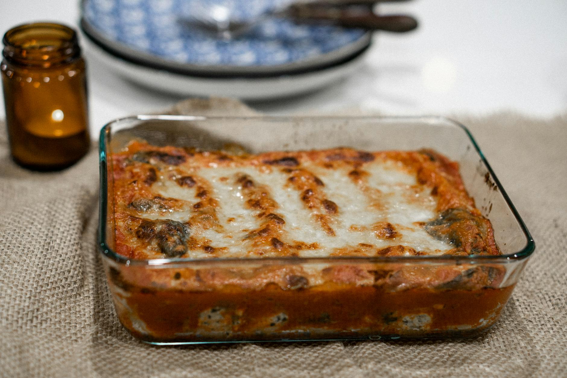 A glass tray of lasagna sitting on top of the table.